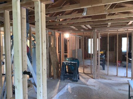 A Colorado Home Remodeling team renovates a house: exposed wooden framing, unfinished walls, and scattered tools show clear signs of progress.