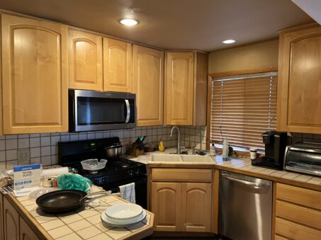 Transform your northern Colorado kitchen with light wood cabinets, stainless steel appliances, a gas stove, handy cookware displayed on the counter, and a window framed by closed blinds.